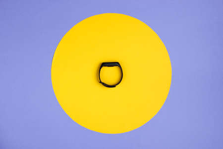 Smart bracelet on a purple background with a yellow circle. Top viewの写真素材