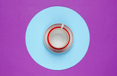 Retro ceramic cup on a purple background with a blue circle in the middle. Flat lay fashion still...
