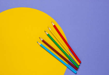 Color pencils on a purple background with a yellow circle. Studio shot