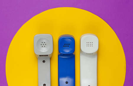 Three Retro telephone handset on a purple background with yellow circle. Pop culture. 80s....