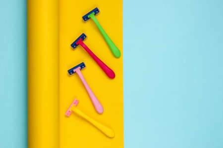 Plastic razors on wrapped paper background. Pastel color trend, minimalistic beauty and fashion...