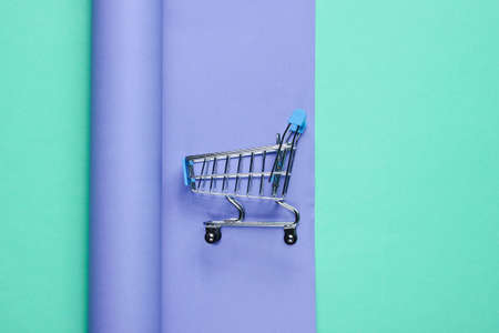 Shopping trolley on wrapped paper background. Color trend, minimalistic beauty and fashion still...