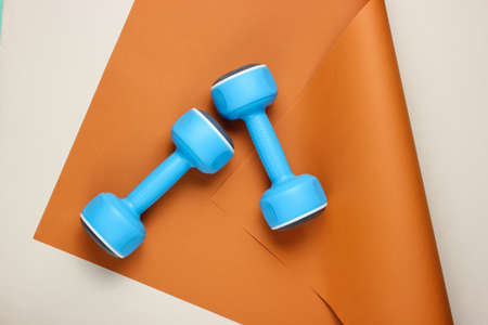 Blue plastic dumbbells on wrapped paper background. Color trend, minimalistic sport and fashion still life. Top viewの写真素材