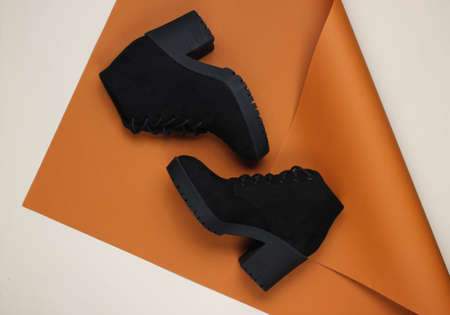 Black suede boots on folded paper background. Minimalistic fashion still life. Flat lay. Top viewの写真素材