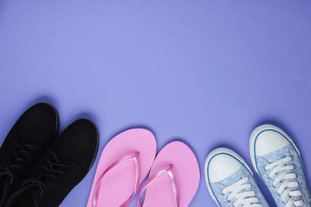Lot of pairs of shoes on purple background. Minimalistic fashion concept. Top view. Copy space