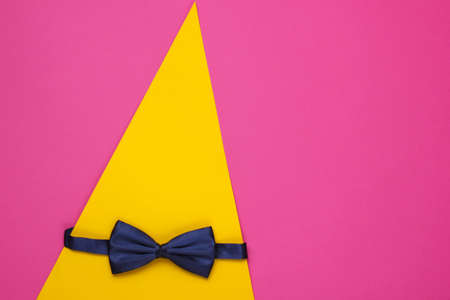 Bow tie on colored paper background. Top view.