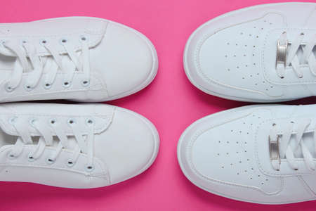 Two pairs of white sneakers on two-color paper background. Top viewの写真素材
