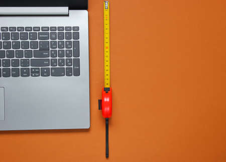 Laptop with industrial ruler on brown background. Top viewの写真素材