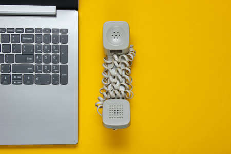 Laptop and handset on yellow background. Minimalistic office concept, call center. Top viewの写真素材