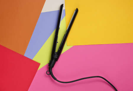Hair straightener on colored background. Top view. Minimalistic beauty and fashion conceptの写真素材