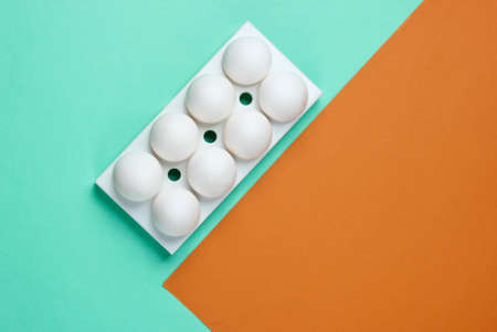 Tray with white chicken eggs on colored background. Minimalistic food concept. Top viewの写真素材