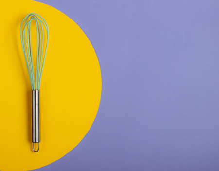 Whisk on blue background with yellow circle. Minimalistic food concept.
