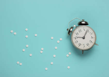 Time to take pills. Pills and alarm clock on blue background. Top viewの写真素材