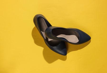 Classic women's high heel shoes on yellow paper background. Stylish shoes. Studio shot. Minimalistic...
