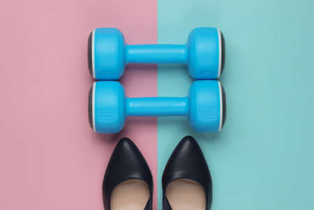 Leddy's sport. Women's high heel shoes with dumbbells on pastel background. Fitness and fashion concept. Top view, minimalismの写真素材