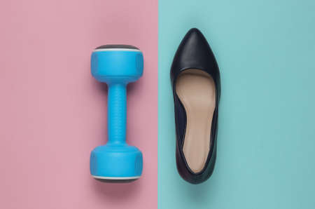 Leddy's sport. Women's high heel shoes with dumbbells on pastel background. Fitness and fashion concept. Top view, minimalismの写真素材