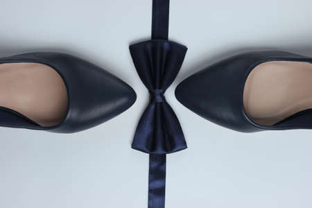 Minimalistic fashion still life. Women's high heel shoes and bow tie on white background. Top viewの写真素材
