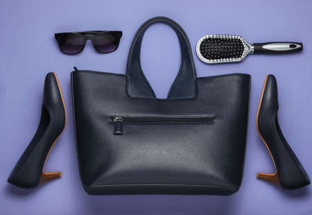 Flat lay style women's accessories on purple background. Bag, leather high heel shoes, sunglasses,...