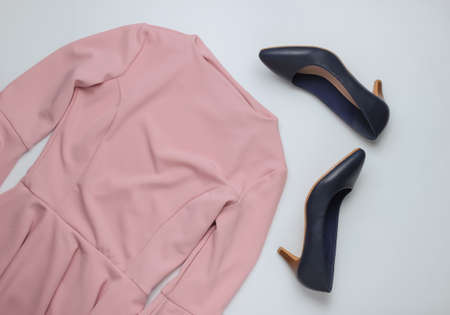 Flat lay style women's clothing, accessories on a white background. Pink dress, leather high heel...