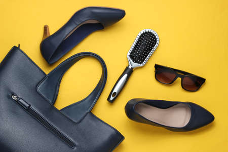 Flat lay style women's accessories on yellow background. Bag, leather high heel shoes, sunglasses, comb. Top viewの写真素材