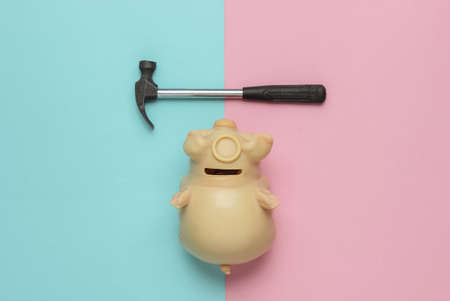 Minimalism fashion concept. Piggy bank with hammer on pink-blue background. Top viewの写真素材