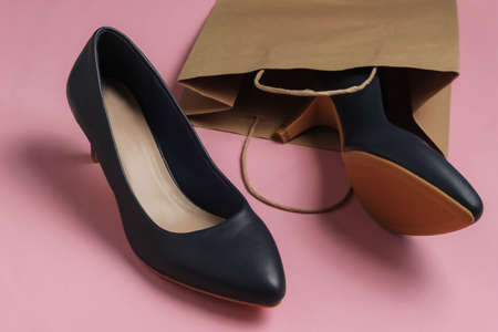 Shopping concept. Fashion studio shot. Women's high-heeled shoes in paper bag for shopping on pink pastel background. Top viewの写真素材