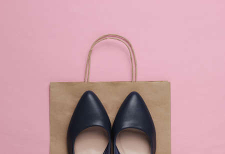 Shopping concept. Fashion studio shot. Women's high-heeled shoes and paper bag for shopping on pink pastel background. Top viewの写真素材