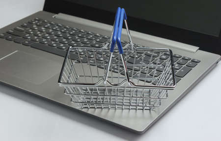 Online shopping concept. Laptop and mini shopping basket on white backgroundの写真素材