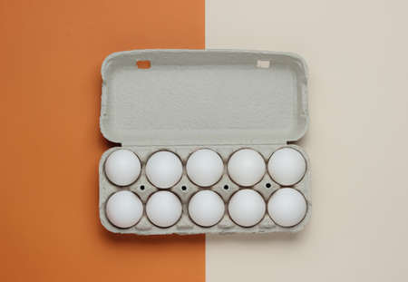 Cardboard tray with eggs on brown beige background. Minimalism cooking concept.