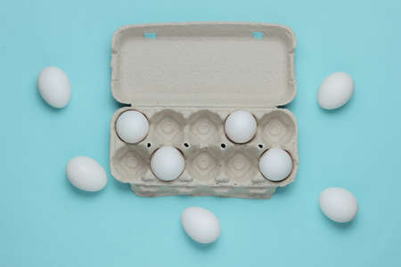 Cardboard tray with eggs on blue pastel background. Minimalism cooking concept.の写真素材