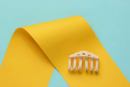 Hair clip on blue-yellow paper background. Top viewの写真素材