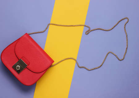 Stylish red bag with chain on colored paper background. Top view. Minimalistic fashion concept.の写真素材