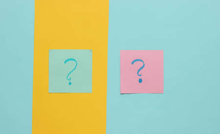 Memo pieces of paper with question marks on a colored background. Top view