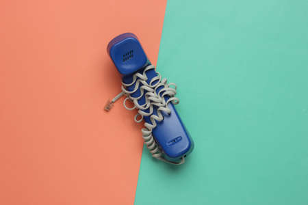 Handset wrapped cable on blue pink paper background. Minimalistic office concept. Top view