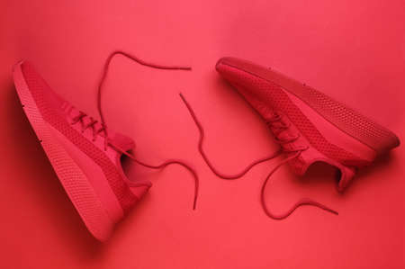 Red sport running shoes with untied laces on red background. Top viewの写真素材