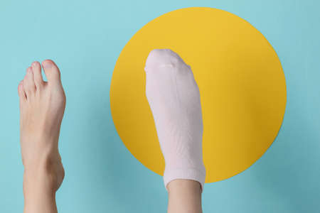 Barefoot foot and foot in sock on blue background with yellow circle