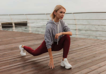 Morning workout. Healthy lifestyle concept. Young attractive woman in sportswear does leg stretching...