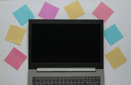 Minimalistic office concept. Lptop and lot of memo papers on white background. Top view