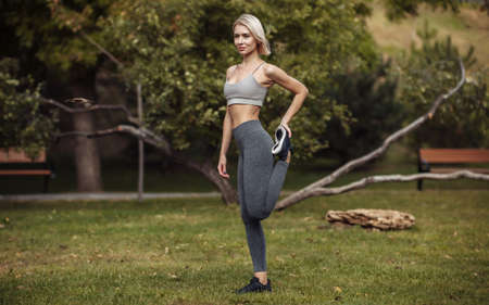 Outdoor training. Young fitness woman doing an aerobic workout before training. Warm up. stretching...