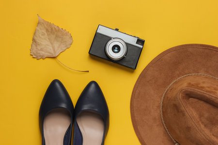 Leather high heel shoes, hat, retro camera on yellow background. Travel concept. Autumn Trip, tourism. Top viewの写真素材