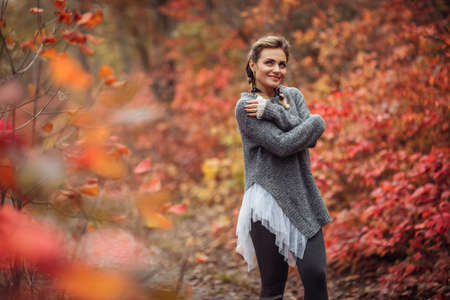Young cheerful frozen woman in the autumn forest with reddened leaves. Art portraitの写真素材