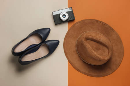 Leather high heel shoes, hat, retro camera on a beige-brown background. Travel concept. Trip to new cities, tourism. Top viewの写真素材