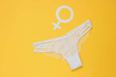 Women's sexy lace panties and gender Femen symbol on yellow background. The concept of feminism. Top...