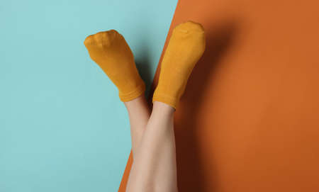 Female slim legs in orange socks on a blue-brown background. Top view