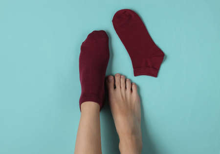 One female leg in a red sock and the second barefoot on a blue studio background. Top viewの写真素材