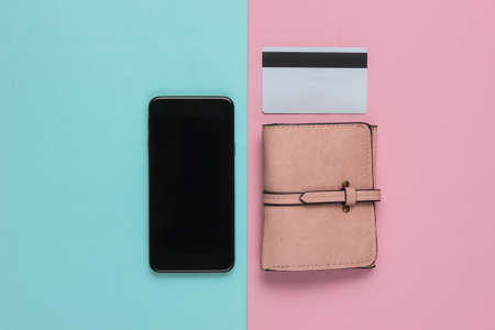 Smartphone, wallet and bank card on pink blue pastel background. Contactless payment. Online...