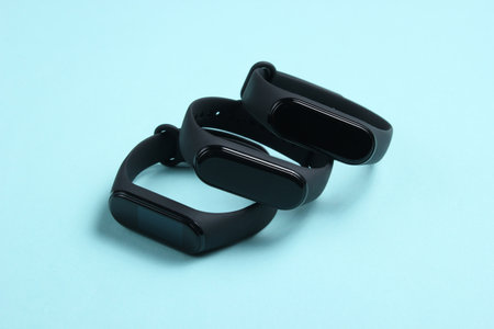 Three smart bracelets on blue background. Modern gadgets for sports and everyday activitiesの写真素材