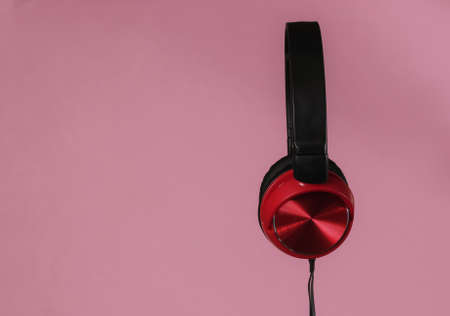 New headphones with cable. Minimalist photo of earphones  on pink pastel background with copy space....