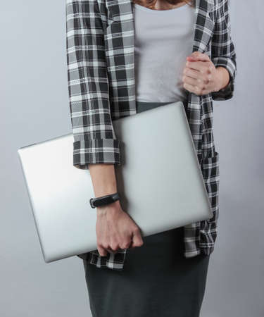 Business business woman in formal clothes holds a laptop while standing on a white background. Crop...