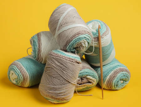Skein of woolen threads of pastel colors and crochet hook on yellow background. Housewives Hobbiesの写真素材